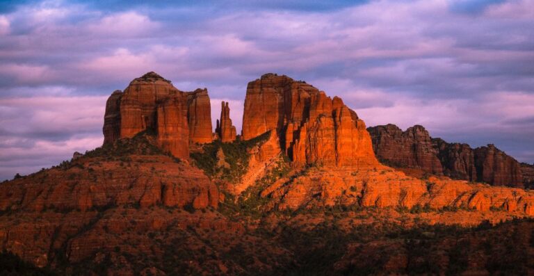 sun casting a red glow on cathedral rock in sedona