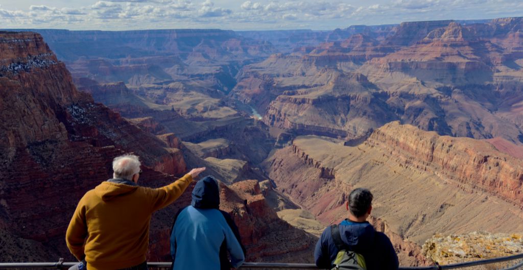 group of three people looking out at the grand canyon on a guided tour