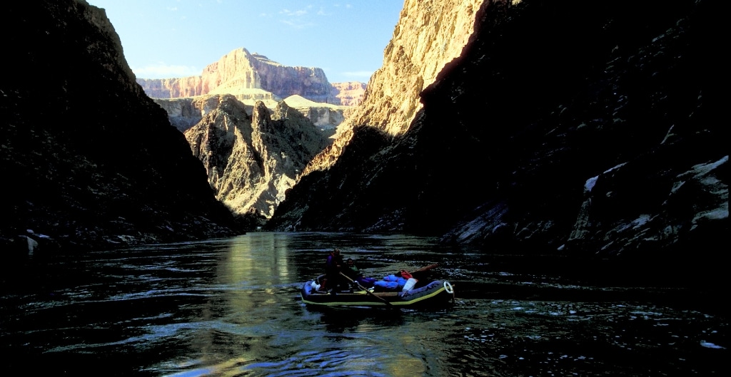 a raft hidden in shadows of the grand canyon walls