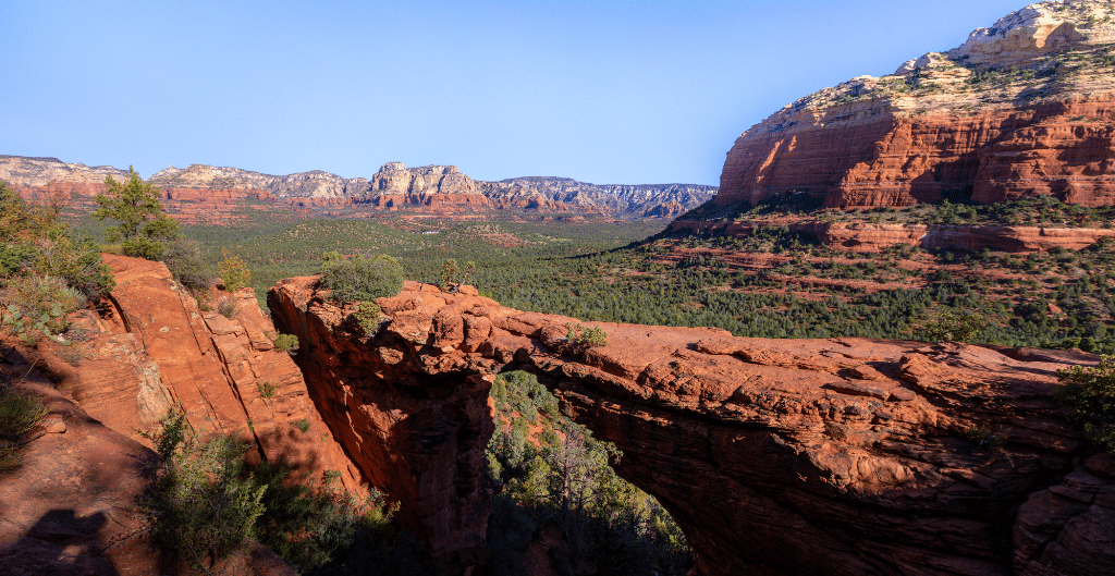 looking out onto devil's bridge, an iconic hike in sedona with more red rock and sandstone cliffs in the background