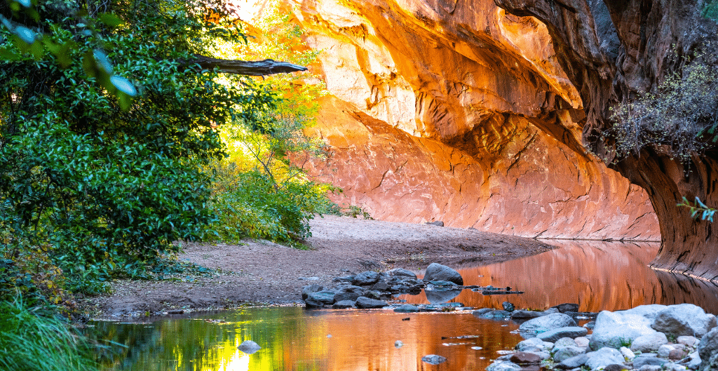 water flowing under red rock cliff walls on the west fork trail in sedona